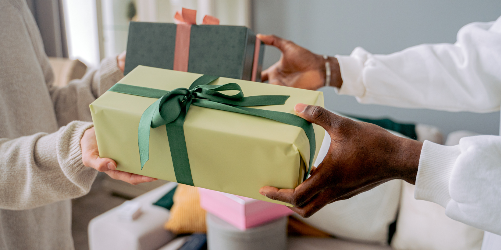 A person handing another person a beautifully wrapped gift to celebrate. 